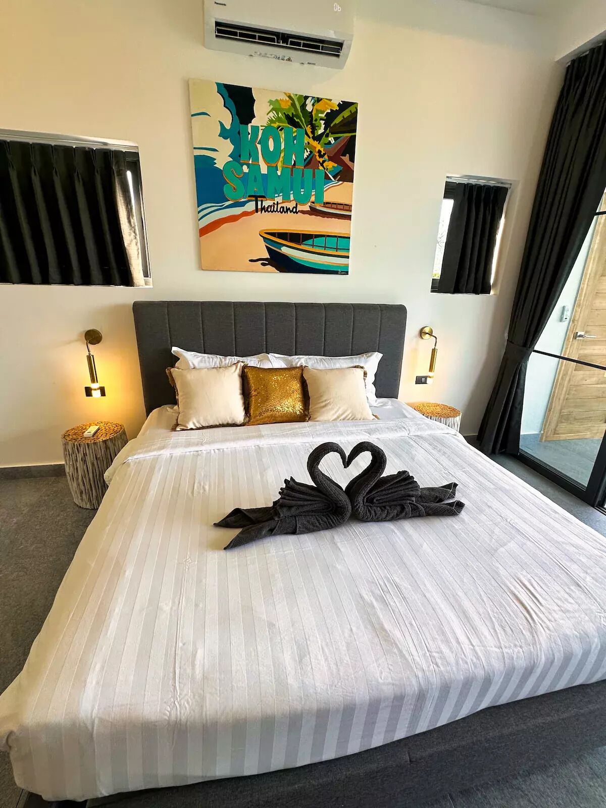 Une chambre d’hôtel avec un lit, une décoration murale représentant un bateau et des palmiers, et une fenêtre avec des rideaux.