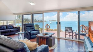 A spacious living room with a large sliding glass door leading to a balcony with a view of the sea.