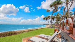 A beach view with a patio area featuring two lounge chairs and a lifebuoy.
