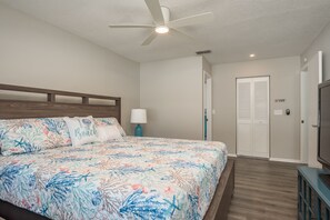 Un dormitorio con cama, ventilador de techo, mesita de noche, lámpara y armario.