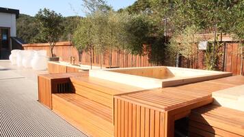 A wooden deck with built-in seating and a rectangular planter.