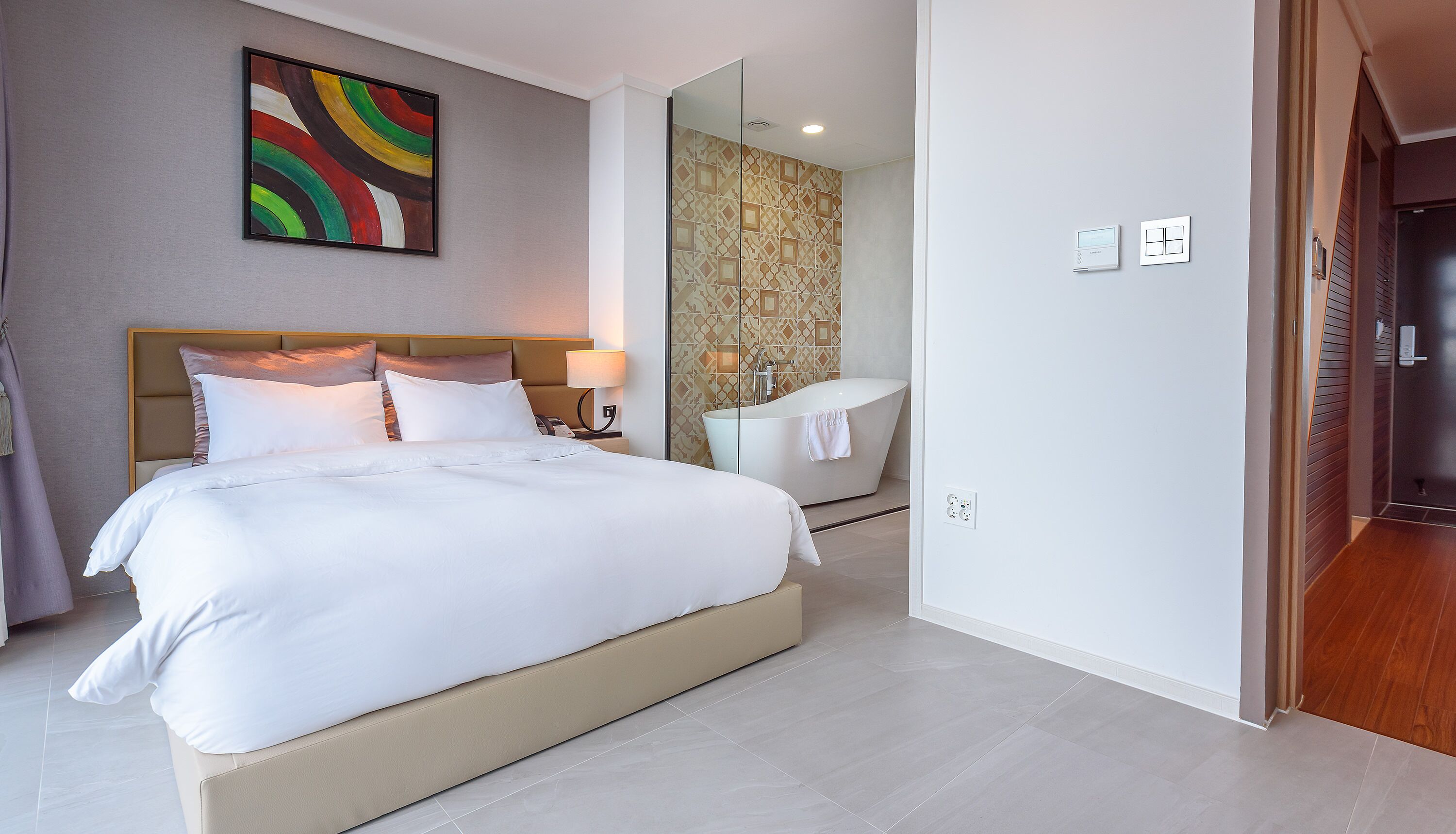 Ein modernes Hotelzimmer mit einem großen Bett, einem Badezimmer mit Badewanne und Dusche.