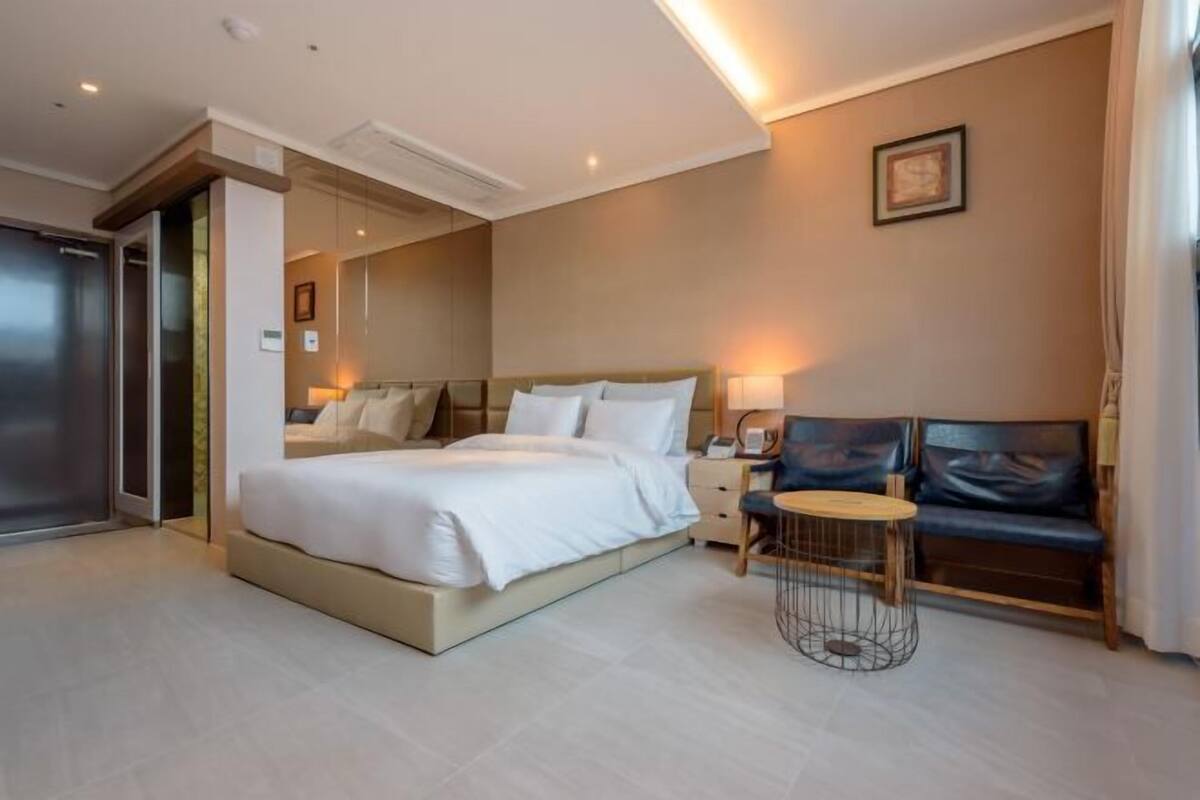 A hotel room with a bed, bedside table, lamp, and a small round table.