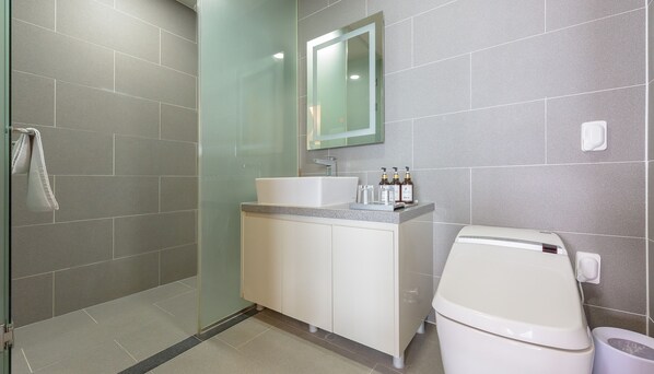 Un baño moderno con cabina de ducha de vidrio, un lavabo blanco y un inodoro.