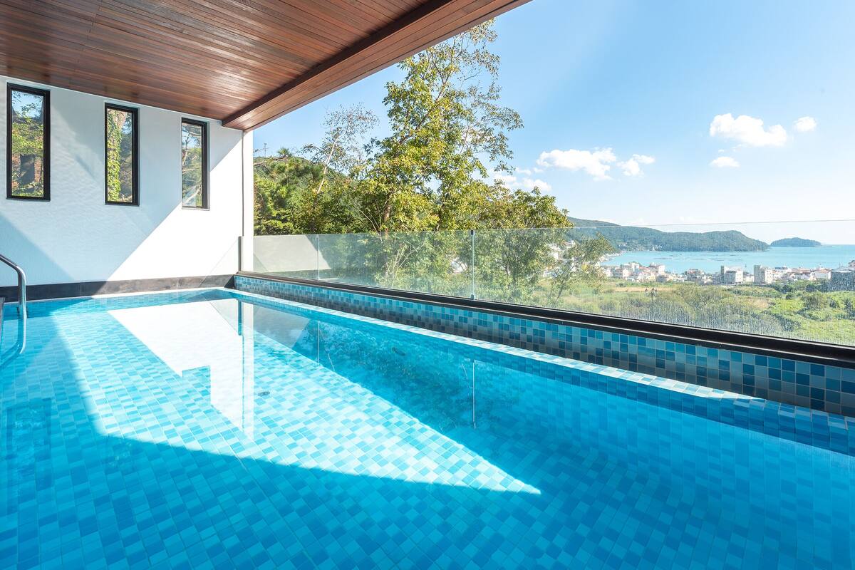 A swimming pool with a clear view of a cityscape and hills in the background.