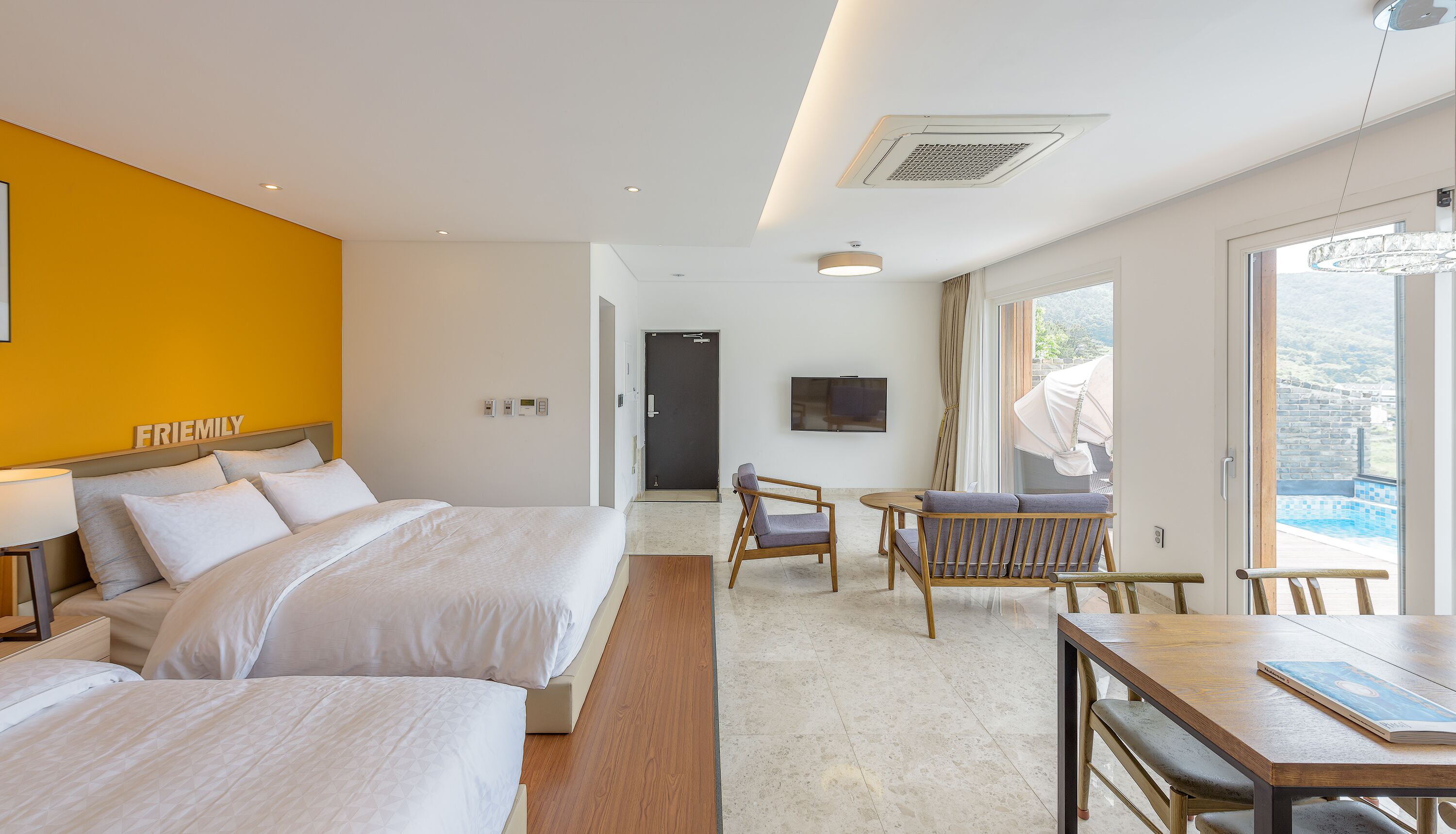 A hotel room with two beds, a dining table, and a TV.