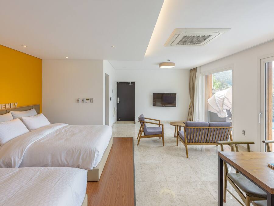 A hotel room with two beds, a dining table, and a TV.