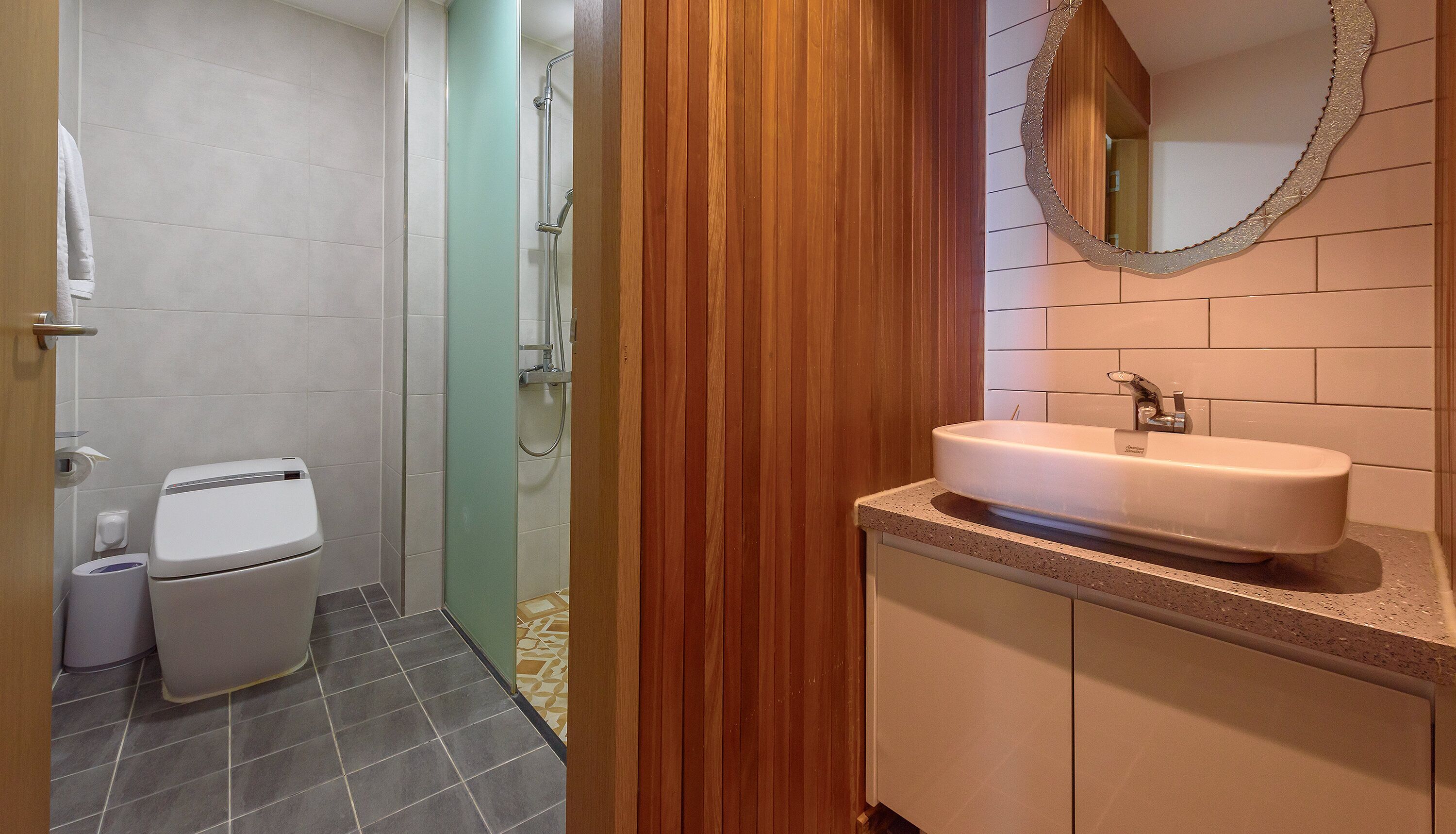 A bathroom with a toilet, a shower, a sink, and a mirror.
