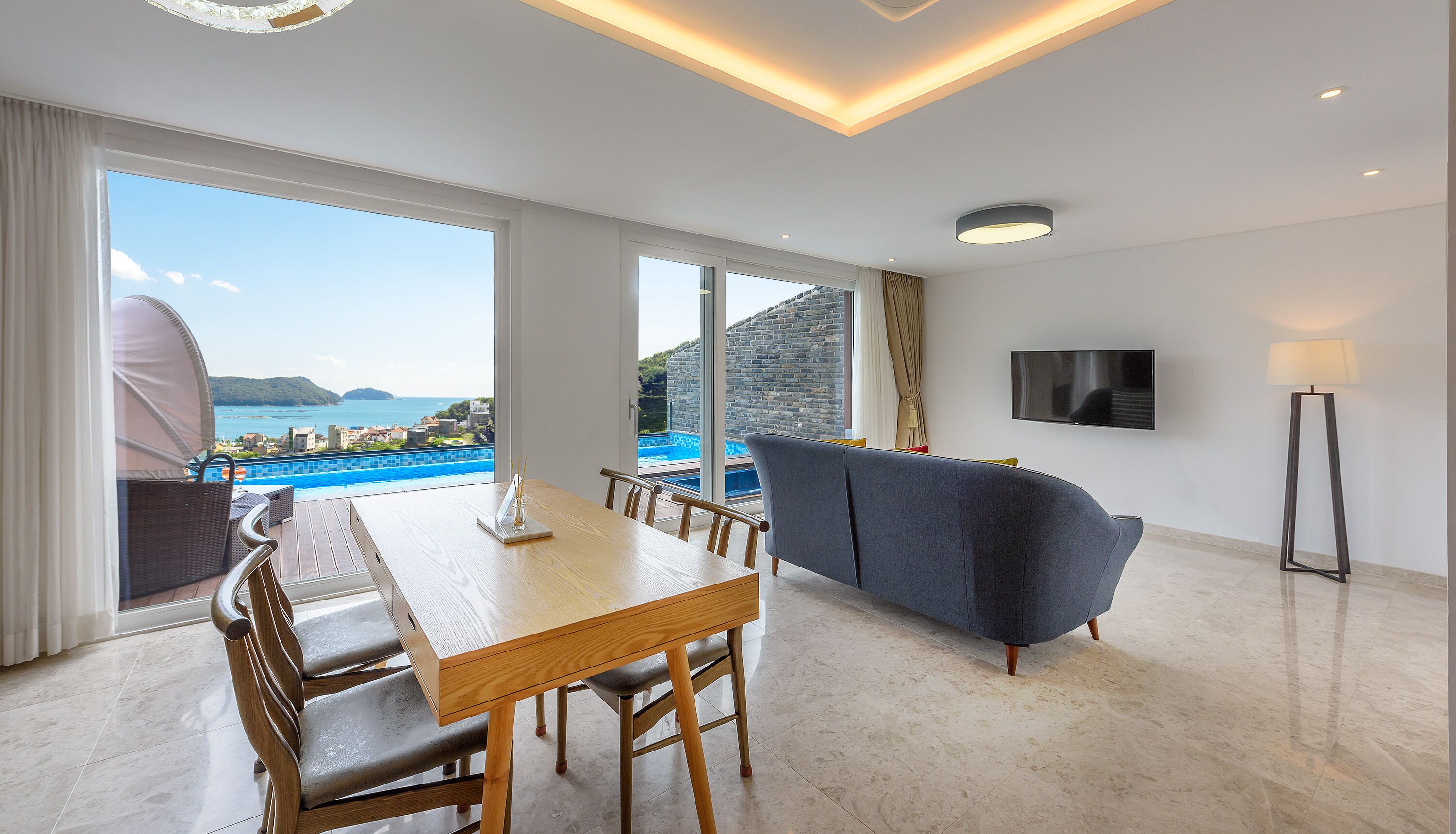 A modern living room with a pool view, a dining area, and a flat-screen TV.