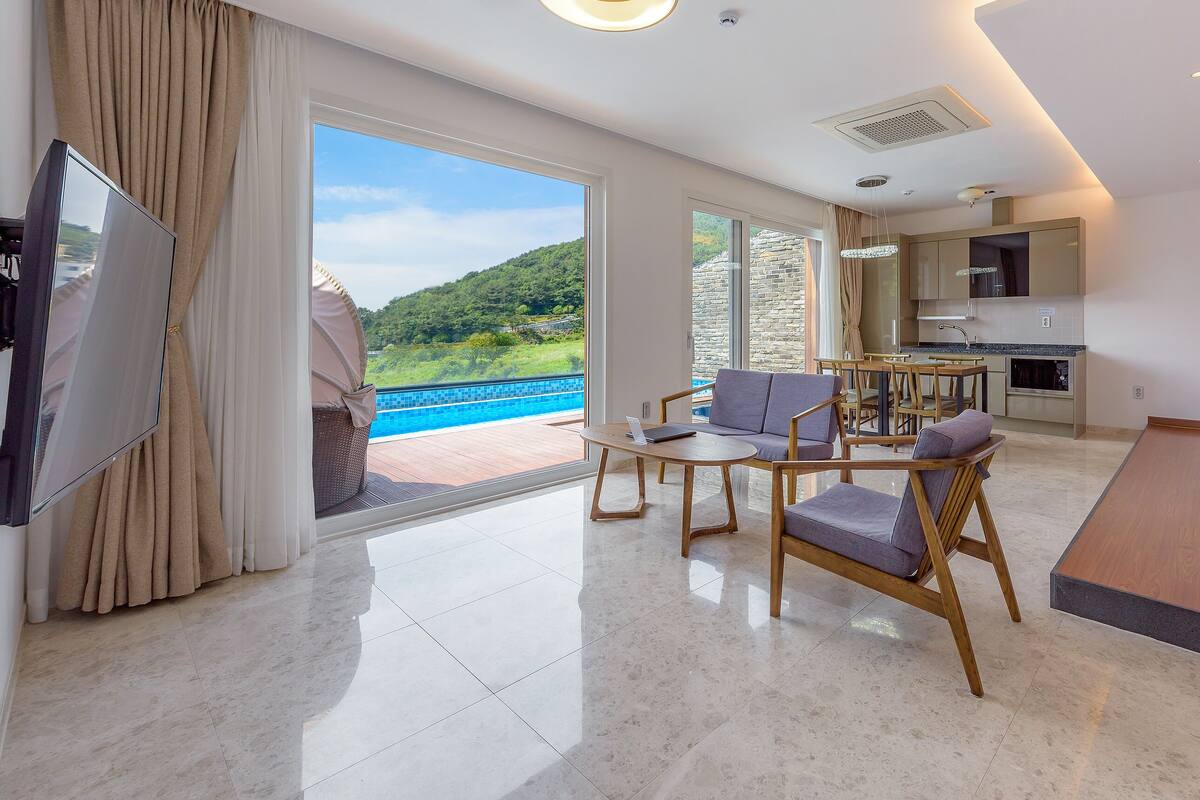 A modern hotel room with a balcony, a dining area, and a kitchen.