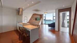 A modern kitchen with a built-in island, wooden accents, and a view of the sea. - Friemily Pool Villa & Hotel (Geoje)