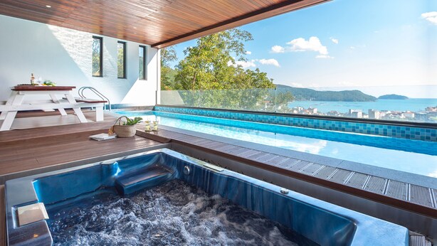 A modern infinity pool with a hot tub, wooden deck, and a view of the sea and hills. - Friemily Pool Villa & Hotel (Geoje)