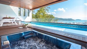 A modern infinity pool with a hot tub, wooden deck, and a view of the sea and hills. - Friemily Pool Villa & Hotel (Geoje)