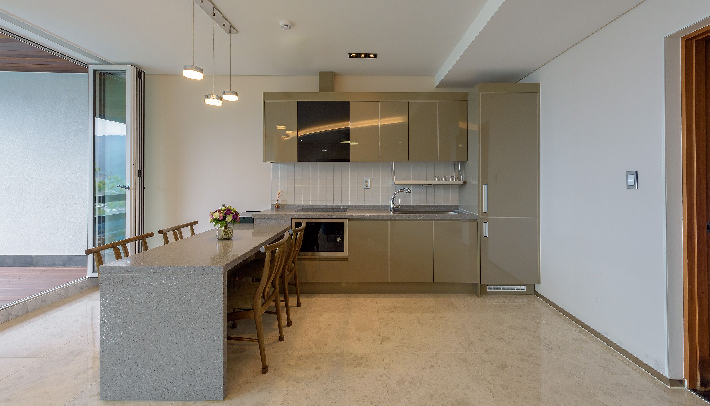 Una cocina moderna con una isla central, sillas de madera y un florero.