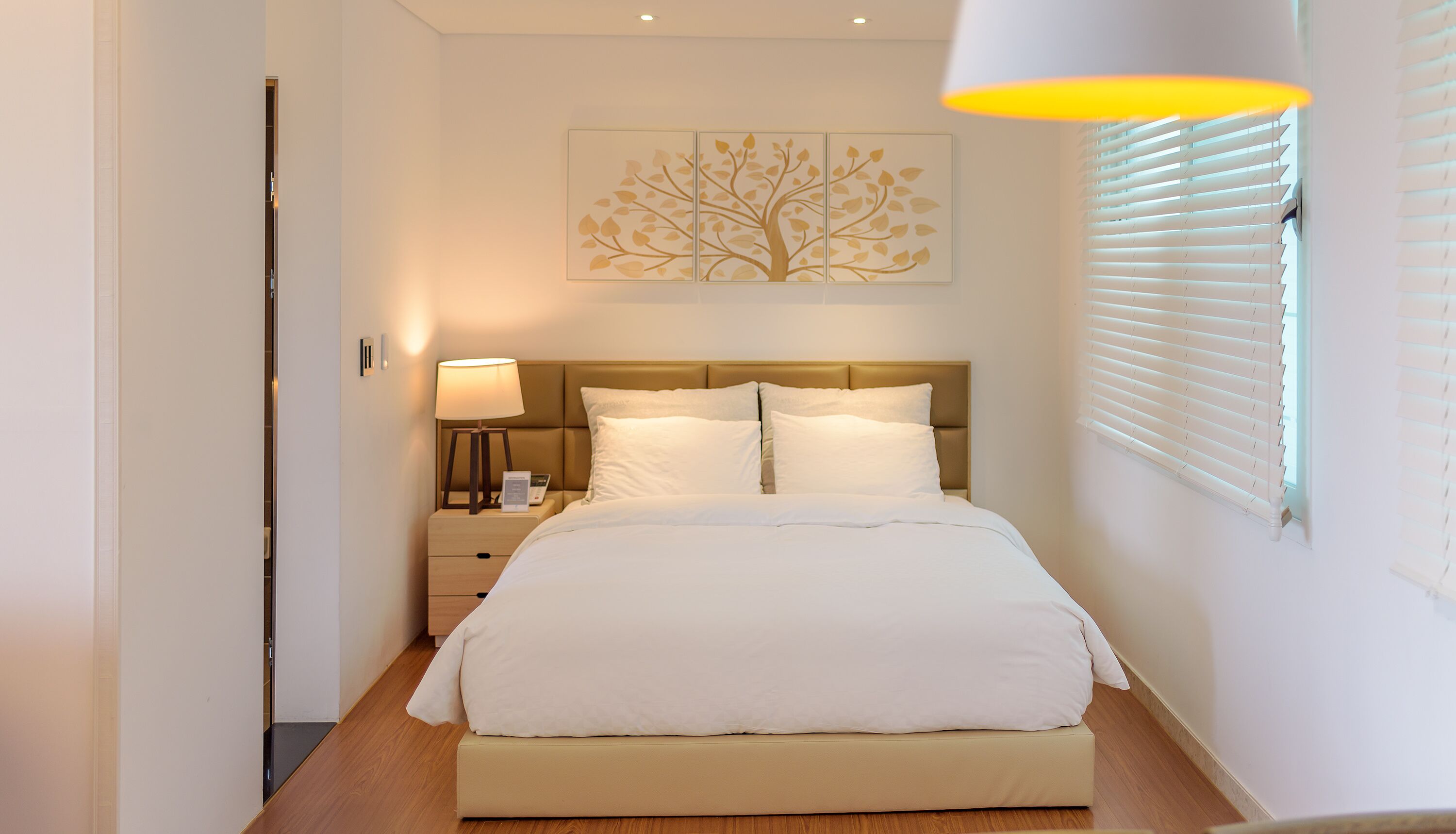 Ein Schlafzimmer mit Bett, Nachttisch, Lampe und einem Wandbild.