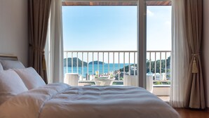 Un dormitorio con una cama grande, un balcón con vistas al mar y una mesa con bebidas.