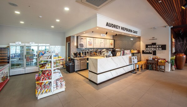 Una cafetería con mostrador de mármol, vitrinas refrigeradas y gran variedad de productos alimenticios.