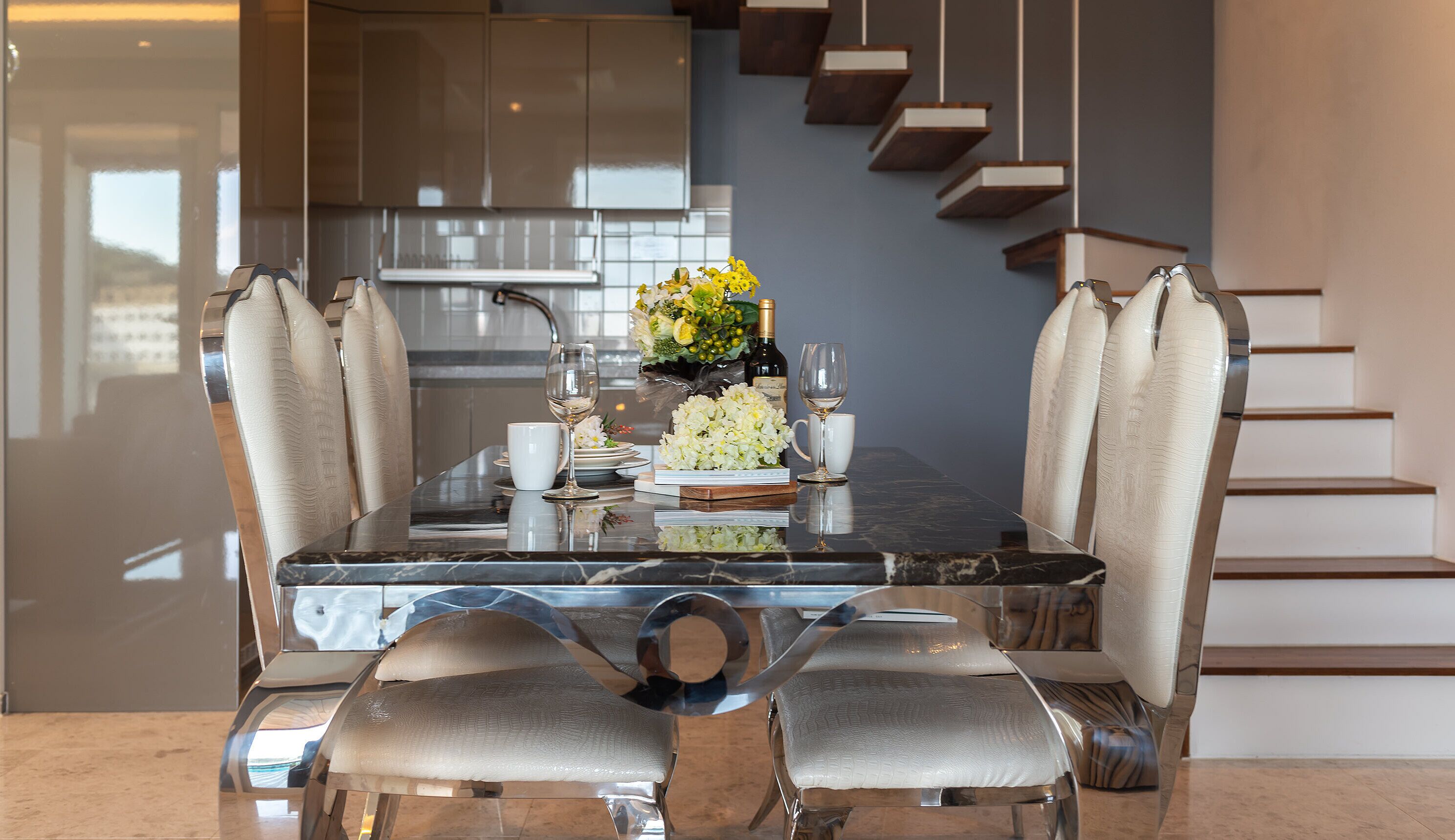 Un espace repas moderne avec une table en marbre, des chaises rembourrées et un élément décoratif central.