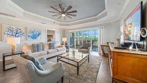 A spacious living room with a ceiling fan, a large TV, and a comfortable seating area.