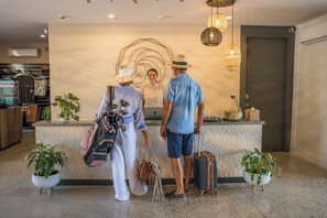 A reception area with a counter, potted plants, and a modern interior design. - VIDA Cayman (West Bay)