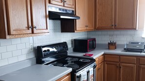 Una cocina con armarios de madera, estufa, microondas y tostadora.