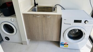 Un espace buanderie compact comprenant un lave-linge, un évier et un meuble de rangement.