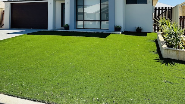 Une maison moderne à deux étages, dotée d’un grand garage, d’une pelouse bien entretenue et surplombée d’un ciel bleu dégagé.