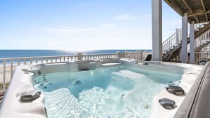 Un jacuzzi avec vue sur l’océan, une terrasse couverte et un escalier.