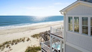 Une maison de plage avec une terrasse donnant sur l’océan, une piscine et une plage de sable.