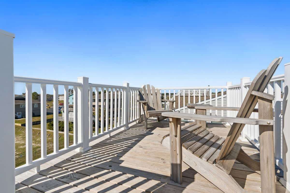 Une terrasse en bois avec des rampes blanches, un banc et une table.