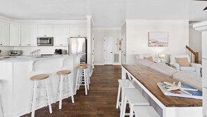 A modern kitchen with white cabinetry, stainless steel appliances, and a wooden island with stools. - Better Together by Brunswick Vacation Rentals: Heated Pool, Great Views & Access (Ocean Isle Beach)