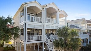 A two-story building with balconies, a covered porch, and a flag. - Better Together by Brunswick Vacation Rentals: Heated Pool, Great Views & Access (Ocean Isle Beach)