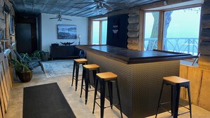 Eine Bar mit Hockern, einer Holztresen und Blick ins Freie.