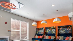 Een pooltafel in een ruimte met een vloer met geometrisch patroon, oranje muren en graffiti kunst.