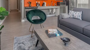 Een moderne keuken met witte kasten, een oranje spatwand en roestvrijstalen apparatuur.