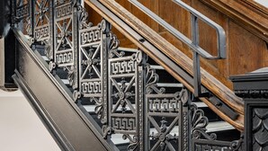 A staircase with ornate black metal railings and a wooden handrail. - Kasa Comfy Studio Nearby Bakery Square The Maverick (Pittsburgh)