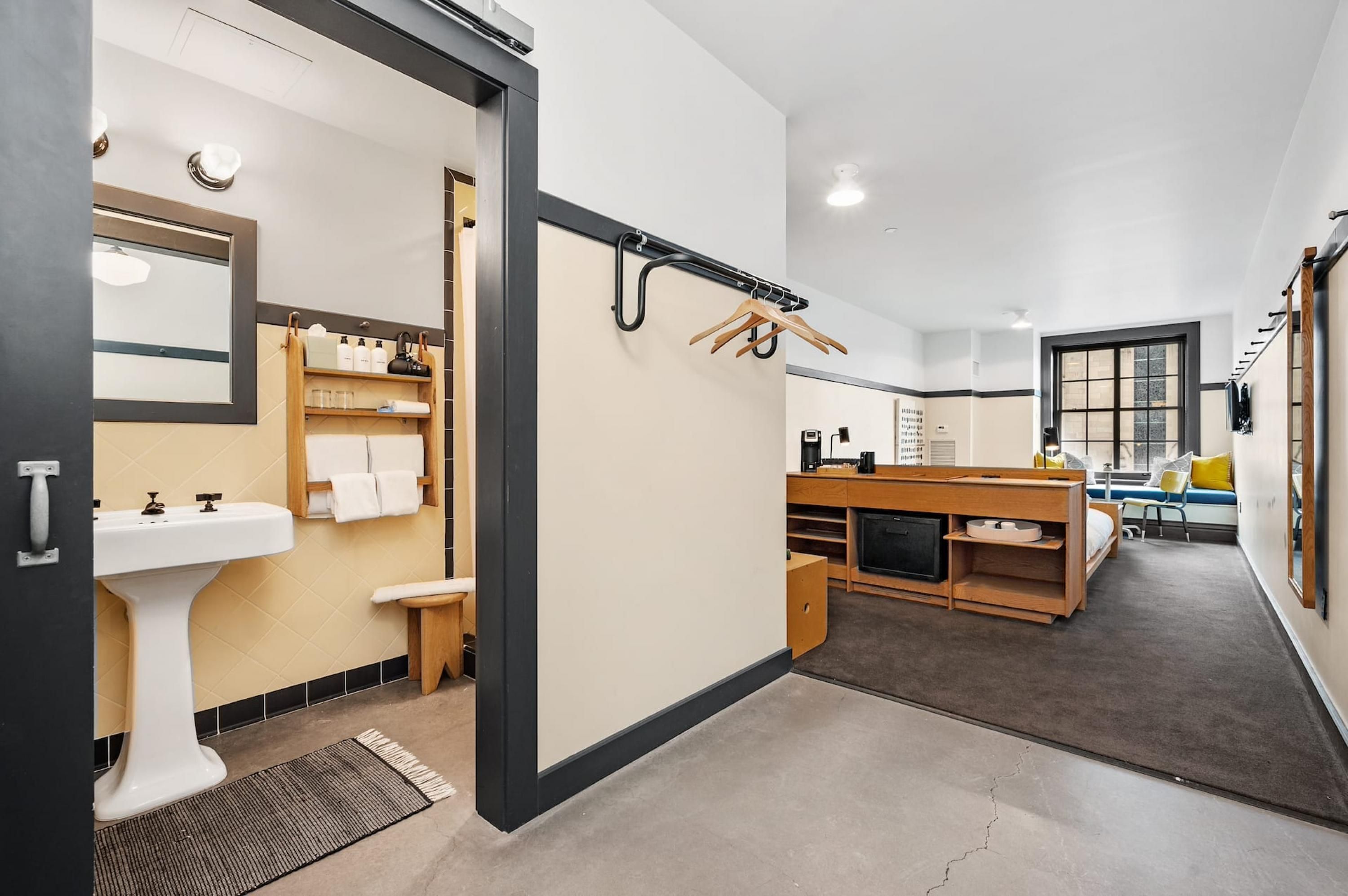 A modern bathroom with a sink, towel rack, and storage shelves.