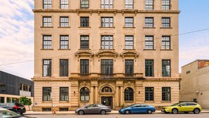 A multi-story building with a symmetrical facade, large windows, and a central entrance with decorative elements.