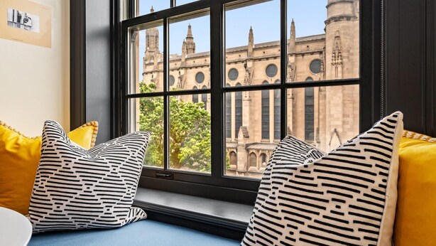 A window seat with patterned cushions and a view of a historic building.
