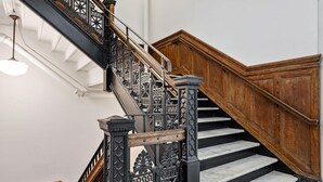 Uma escadaria imponente com grades ornamentadas em preto e degraus de madeira.
