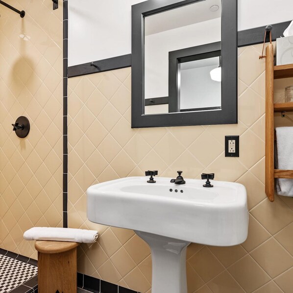 A bathroom with a white sink, a mirror, and a towel rack.