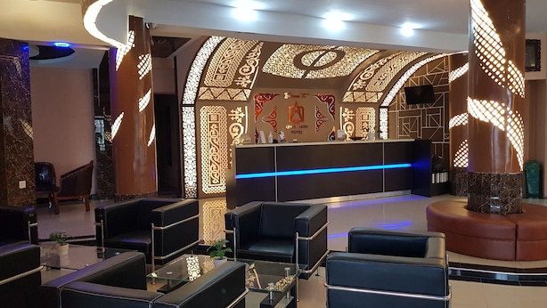 Een hotel lobby met een receptiebalie, een zithoek en decoratieve wandpanelen.