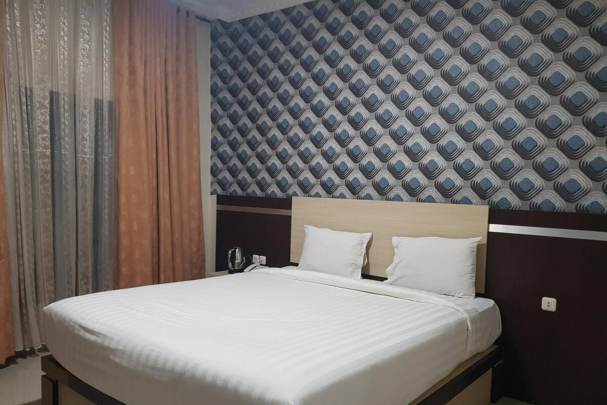 Ein ordentlich bezogenes Bett mit weißen Leinen in einem Hotelzimmer.