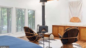 Una habitación acogedora con chimenea, sillones de mimbre y vistas a través de amplias ventanas.