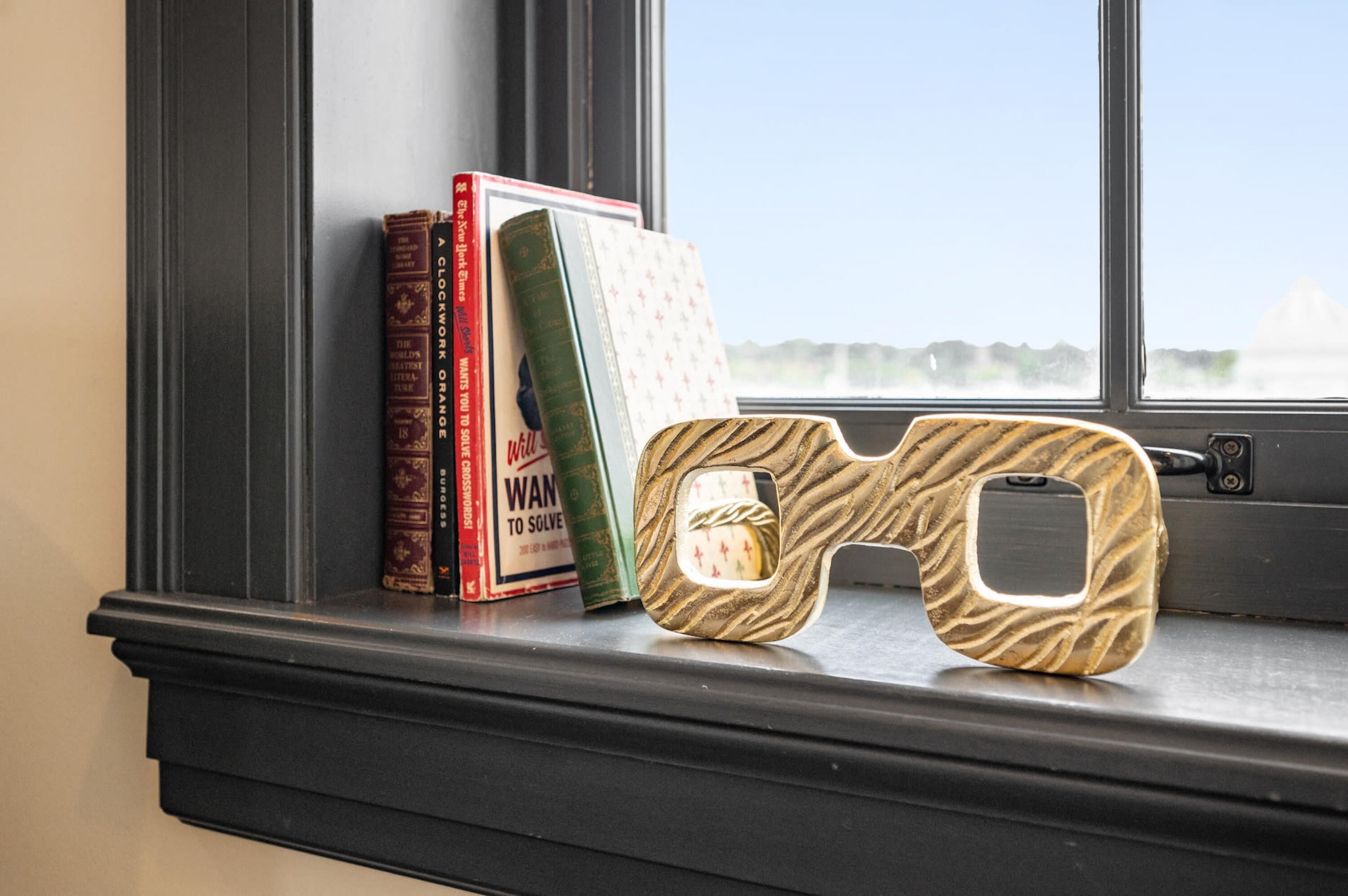 En fönsterbräda med ett par 3D-glasögon, en röd bok med titeln ”A Clockwork Orange” och en grön bok med titeln ”Wand to Solve”.