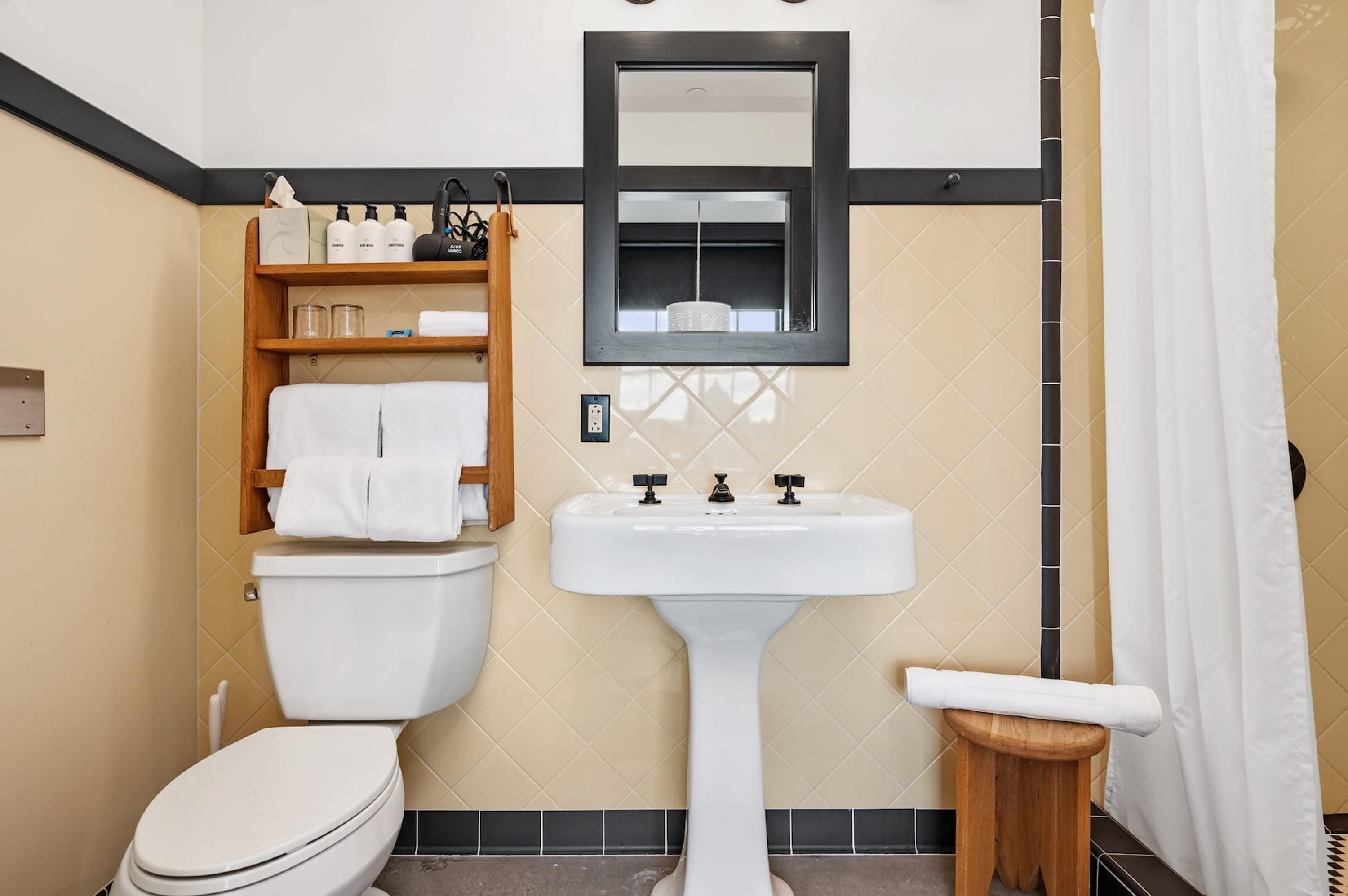 A bathroom with a toilet, sink, and shelf with toiletries.