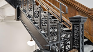 A staircase with ornate black metal railings and wooden steps. - Kasa Trendy Studio Steps to Bakery Square The Maverick (Pittsburgh)
