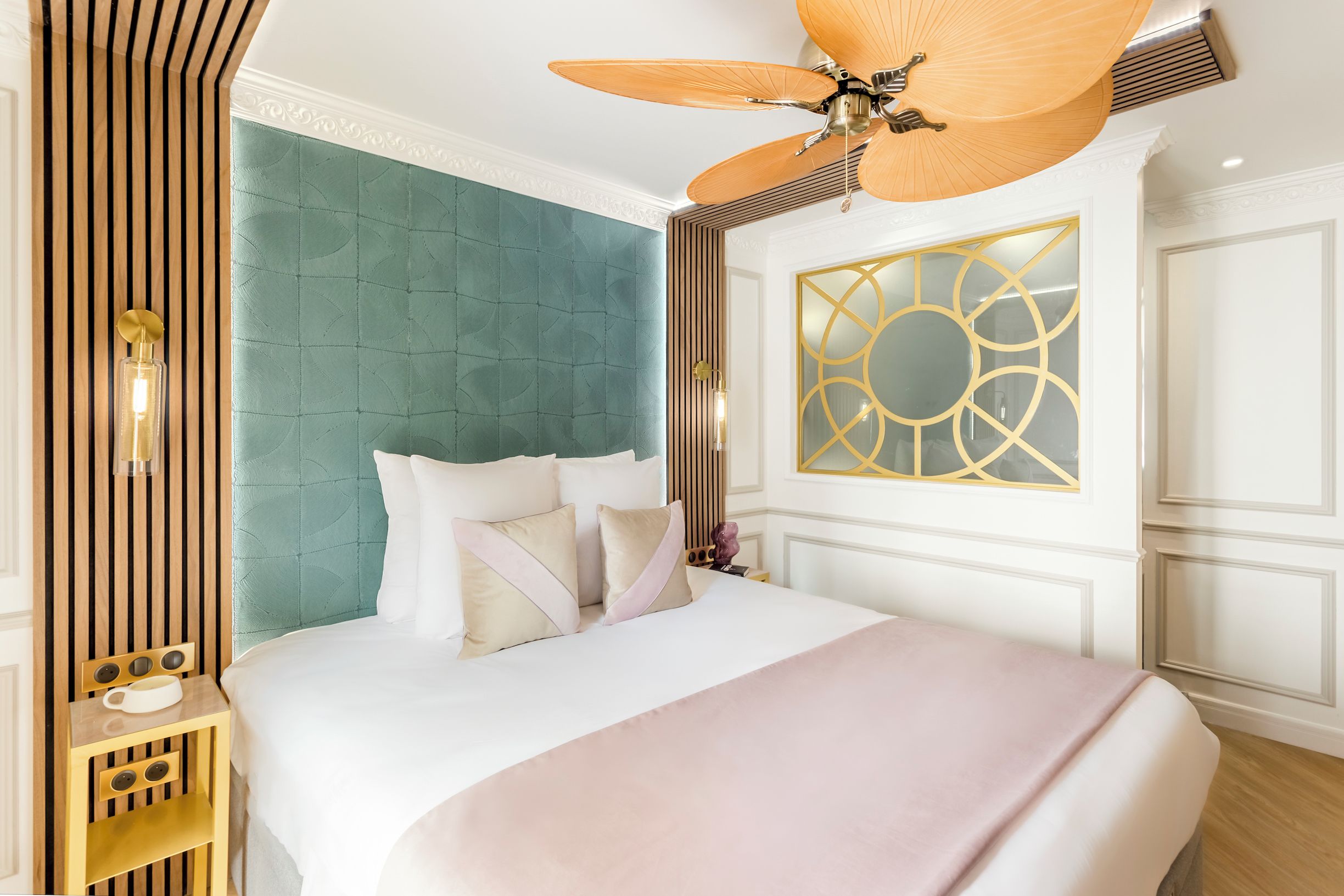 A neatly arranged bedroom with a large bed, a ceiling fan, and a decorative wall panel.