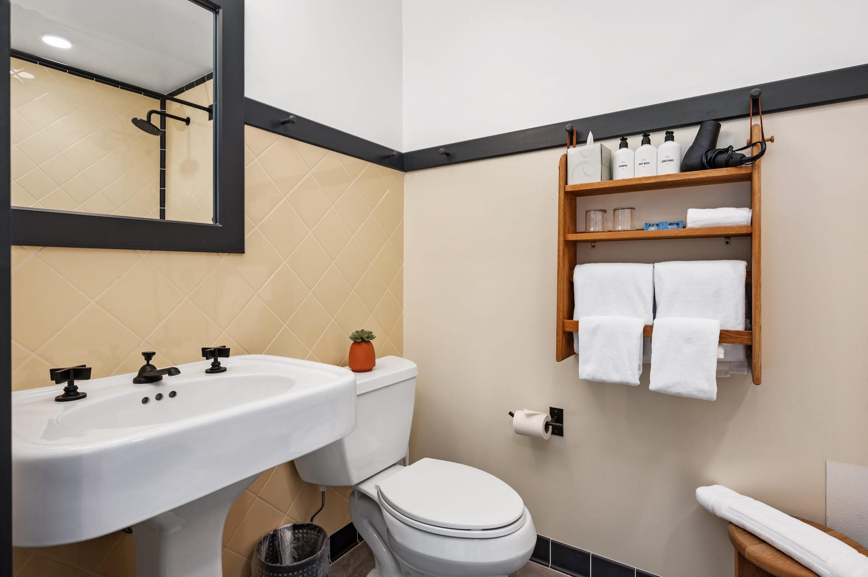 Une salle de bain équipée d’un lavabo, de toilettes et d’une étagère où sont rangés les articles de toilette.