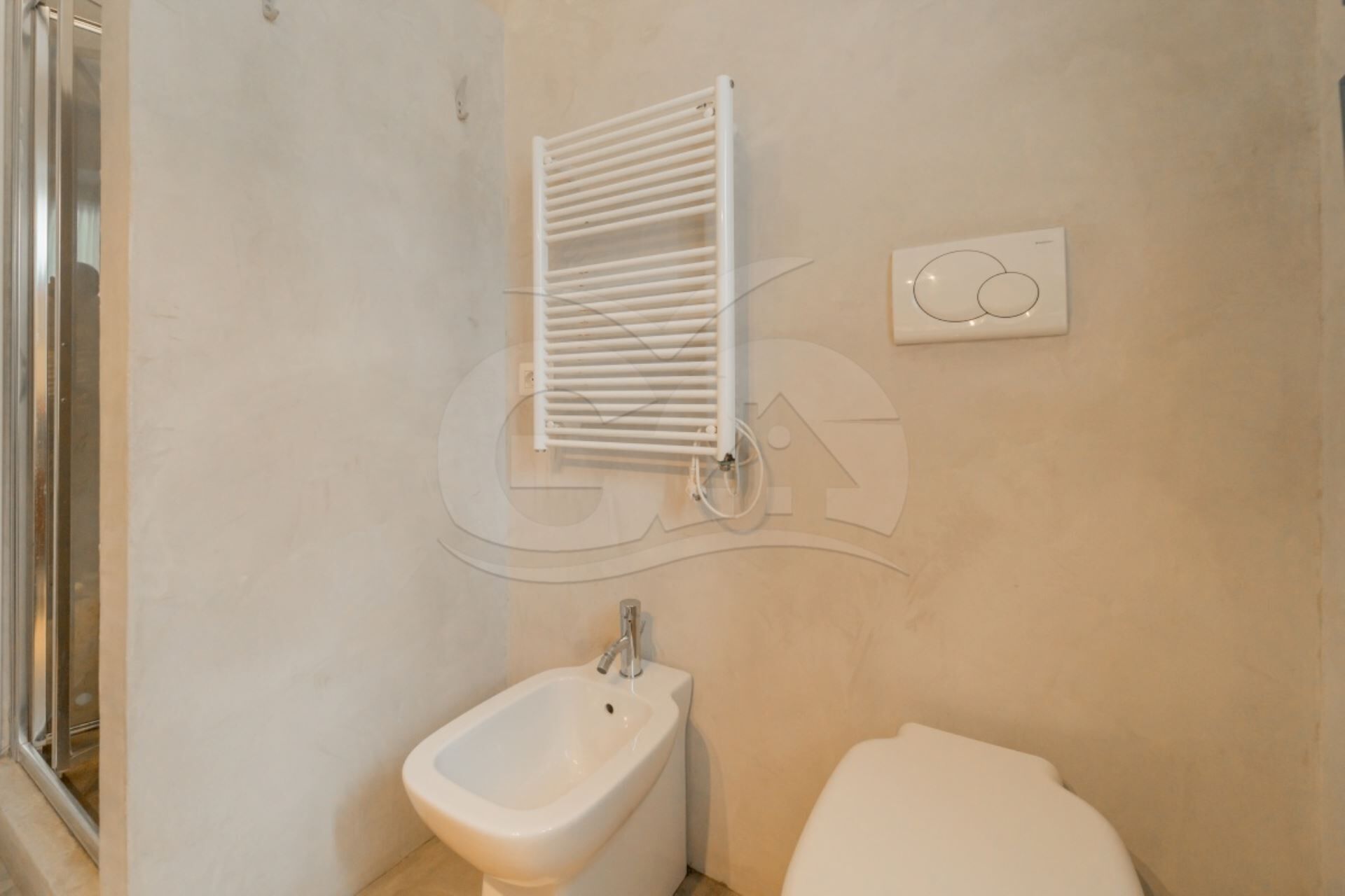 Un baño con bidé, toallero y retrete.